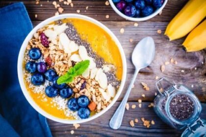 Wandbild: Mango-Smoothies-Schüssel mit Blaubeeren, Müsli, Chiasamen